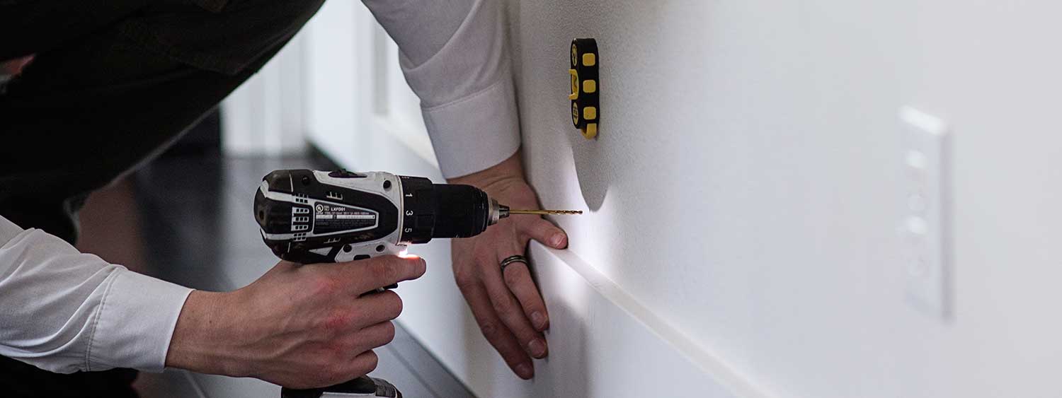 An Aspen Pest Control service technician drilling a tiny 1/8-inch hole in the wall for a foam injection at a home in Camas, WA