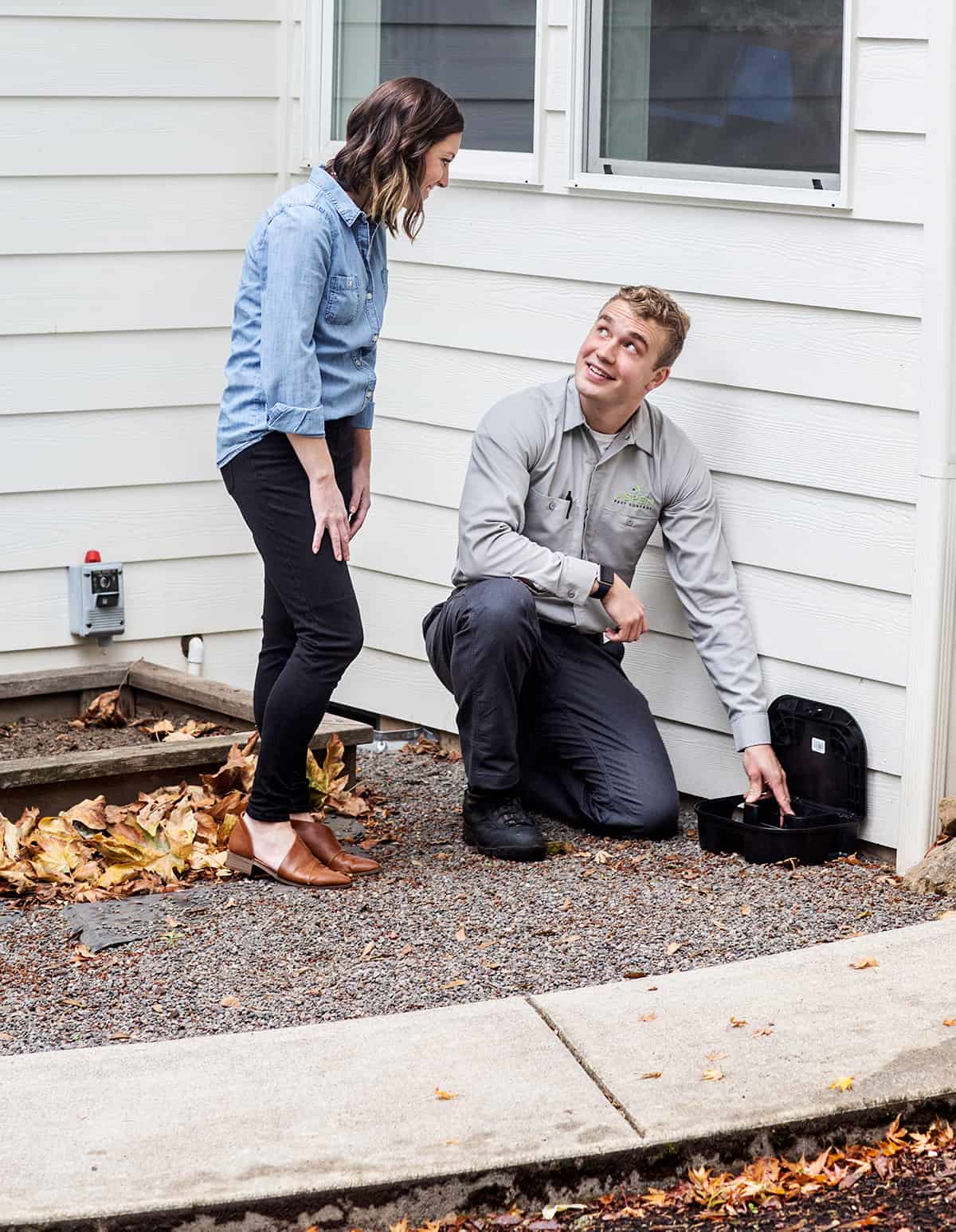 Aspen Pest Control Technician Setting Pest Bait Trap While Talking to Vancouver WA Homeowner Aspen Pest Control Technician Setting Pest Bait Trap While Talking to Vancouver WA Homeowner